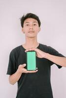 A Southeast Asian man holding a greenscreen phone. Perfect for adding custom content, app interfaces, or marketing messages, showcasing technology use in a versatile context. photo