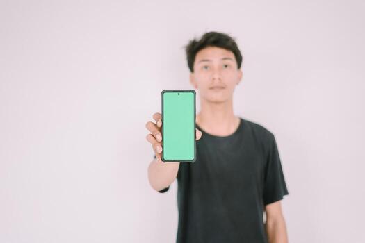 A Southeast Asian man holding a greenscreen phone. Perfect for adding custom content, app interfaces, or marketing messages, showcasing technology use in a versatile context. photo