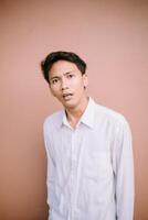 Man wearing a white shirt, displaying a strange expression as he observes something photo