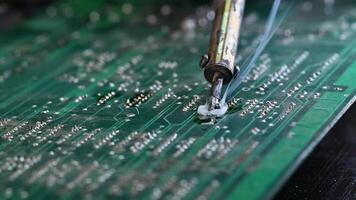 Soldering circuit board on the table, close up. soldering iron and puts it on microcircuit. video