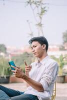 A man points at his smartphone with a suspicious look, questioning what's happening photo