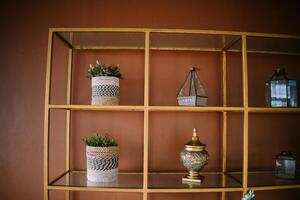 An arrangement of artificial plants and assorted decorations displayed on a metal shelf, adding a touch of greenery and charm to interior decor photo