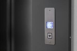 Metal panel with an elevator call button and an indicator of the floor on which the elevator car is located in blue photo