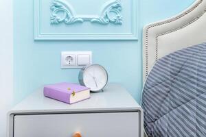 Alarm clock with a book on the bedside table photo
