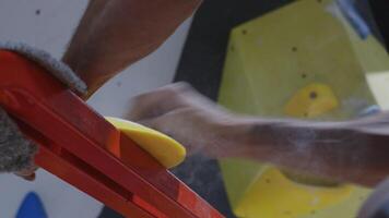 Close-up of hands installing a climbing hold on an indoor wall, showcasing the precision and care involved in setting up a climbing gym video