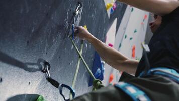 Close-up of climber's hand gripping a hold on an indoor climbing wall, emphasizing technique and precision in a controlled environment video