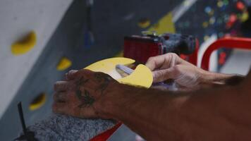 Close-up of hands installing a climbing hold on an indoor climbing wall, highlighting the setup process and craftsmanship in a gym environment video