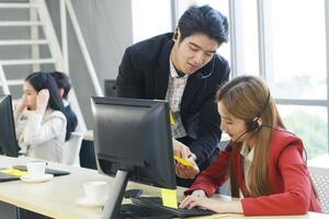 Smiling Business Call Center and technical Support staff or receptionist phone operator Discussing and working for teamwork with computer. Asian customer support team. photo