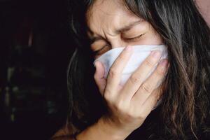 Asian Thai woman wearing a white cloth mask for prevent the Covid-19 or Corona virus in Thailand. She is serious and Coughing about Air Pollution Value Pm 2.5. Health and Respiratory system concept photo