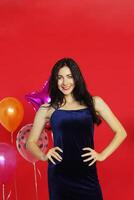 Beautiful Woman Smile and dancing in Chrismas party, birthday time and celebration of New year eve and decoration with colorful ballons and on red background photo