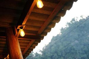 Light bulbs is hanging on wooden beam indoor of cafe and vintage house building photo