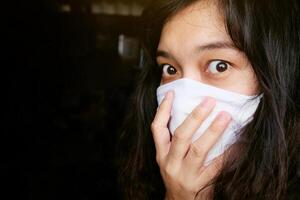 Asian Thai woman wearing a white cloth mask for prevent the Covid-19 or Corona virus in Thailand. She is serious and Coughing about Air Pollution Value Pm 2.5. Health and Respiratory system concept photo