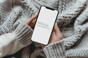 Mockup of black smartphone in two hands on bed with comforter psd