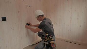 Electrician installing an electrical outlet in a new home construction. He carefully uses tools and techniques to ensure a safe and functional installation. The cabin has a natural wood interior. video