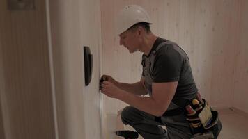 Electrician installing an electrical outlet in a new home construction. He carefully uses tools and techniques to ensure a safe and functional installation. The cabin has a natural wood interior. video