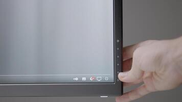 The hand adjusts the monitor to work. ACTION. A black monitor adjusts the hand of a man. A light hand presses the settings buttons on the bottom of the monitor video