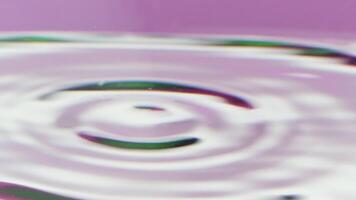 Close-up of drops falling on surface of water with reflection. Stock footage. Circles on surface of water from drop reflect colors. Beautiful colors on circles of drops on isolated background video