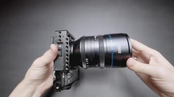 QATAR, DOHA - MARCH 21, 2022. A lens is in the hands of a person. ACTION. The man turns the camera in his hands. A gray background shows a camera with a lens on all sides video