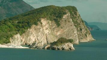 Top view of beautiful cliffs of mountains by sea on sunny day. Creative. Beautiful landscape with rocky shore and green trees. Seashore with rocks and greenery on warm day video