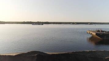 Clearing shoreline of river with ships. Scene. Top view of river with barge and clearing shore. Excavators are clearing riverbank for pier video
