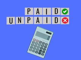 pieces of wood The business concept is represented by square letters with the text PAID AND UNPAID and a calculating machine. photo
