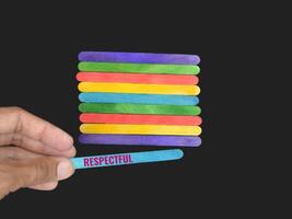 Select a single vibrant ice cream stick adorned with the word RESPECTFUL to symbolise the concept of consistently valuing and honouring one another. The stick should be set against a grey background photo