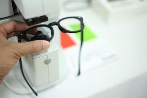 Hand holding eyeglasses in optical store photo