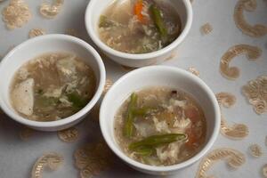 three bowls of soup with vegetables and meat in them photo