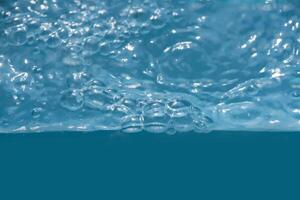 Bluewater waves on the surface ripples blurred. Defocus blurred transparent blue colored clear calm water surface texture with splash and bubbles. Water waves with shining pattern texture background. photo