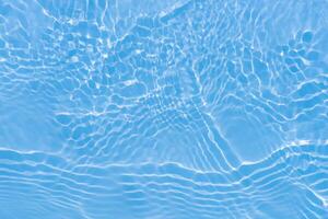 Blue water with ripples on the surface. Defocus blurred transparent blue colored clear calm water surface texture with splashes and bubbles. Water waves with shining pattern texture background. photo