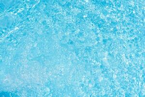 Bluewater waves on the surface ripples blurred. Defocus blurred transparent blue colored clear calm water surface texture with splash and bubbles. Water waves with shining pattern texture background. photo
