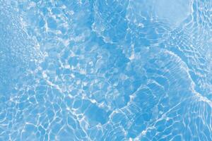 Blue water with ripples on the surface. Defocus blurred transparent blue colored clear calm water surface texture with splashes and bubbles. Water waves with shining pattern texture background. photo
