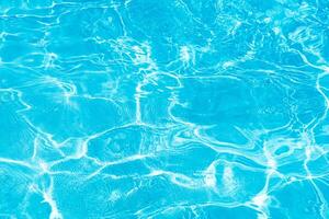 Blue water with ripples on the surface. Defocus blurred transparent blue colored clear calm water surface texture with splashes and bubbles. Water waves with shining pattern texture background. photo