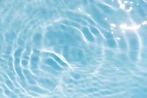Blue water with ripples on the surface. Defocus blurred transparent blue colored clear calm water surface texture with splashes and bubbles. Water waves with shining pattern texture background. photo