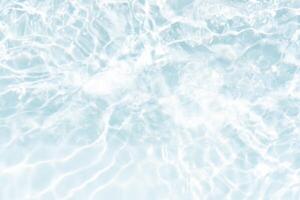 Blue water with ripples on the surface. Defocus blurred transparent blue colored clear calm water surface texture with splashes and bubbles. Water waves with shining pattern texture background. photo