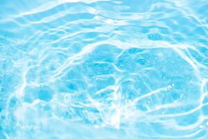 Blue water with ripples on the surface. Defocus blurred transparent blue colored clear calm water surface texture with splashes and bubbles. Water waves with shining pattern texture background. photo
