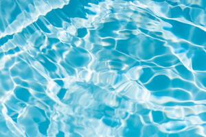 Blue water with ripples on the surface. Defocus blurred transparent blue colored clear calm water surface texture with splashes and bubbles. Water waves with shining pattern texture background. photo