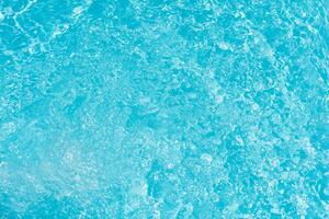 Blue water with ripples on the surface. Defocus blurred transparent blue colored clear calm water surface texture with splashes and bubbles. Water waves with shining pattern texture background. photo