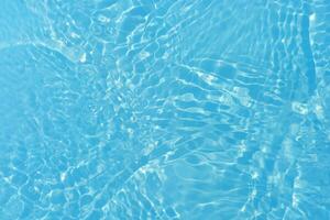 Blue water with ripples on the surface. Defocus blurred transparent blue colored clear calm water surface texture with splashes and bubbles. Water waves with shining pattern texture background. photo