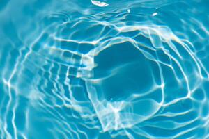Blue water with ripples on the surface. Defocus blurred transparent blue colored clear calm water surface texture with splashes and bubbles. Water waves with shining pattern texture background. photo