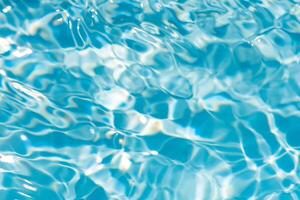 Bluewater waves on the surface ripples blurred. Defocus blurred transparent blue colored clear calm water surface texture with splash and bubbles. Water waves with shining pattern texture background. photo