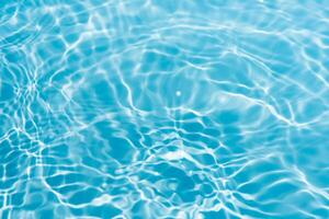 Blue water with ripples on the surface. Defocus blurred transparent blue colored clear calm water surface texture with splashes and bubbles. Water waves with shining pattern texture background. photo