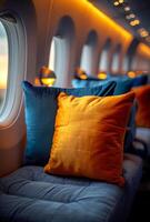 A row of pillows on a plane seat, with one of them being orange photo
