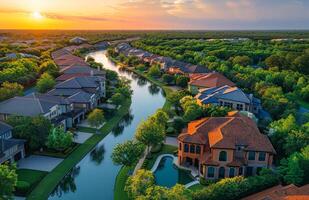 Aerial view of homes in suburban community with winding creek running through it at sunset. photo