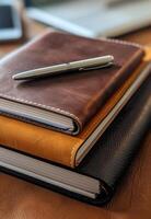 A pen and a notebook are on top of a stack of notebooks photo