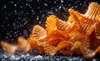 Potato chips are scattered on black background with water drops photo