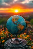 Globe of the world on stone and beautiful sunset in the background photo