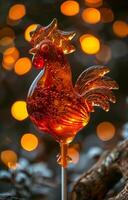 Lollipop in the shape of rooster is on stick against the background of bokeh photo