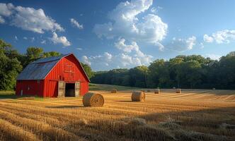 Red barn and hay bales in field. A red barn stands alone in the middle of an open field photo