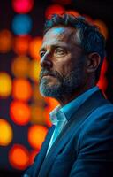 Portrait of mature businessman wearing suit and standing against colorful blurred bokeh background photo